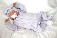 Thumbnail for A baby doll with a pacifier lies on a bed, showcasing its soft features and gentle expression.
