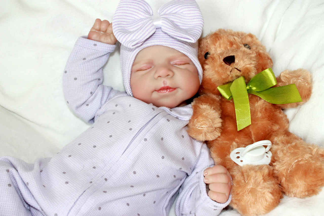 A baby lies peacefully on a soft white blanket, surrounded by a serene atmosphere.