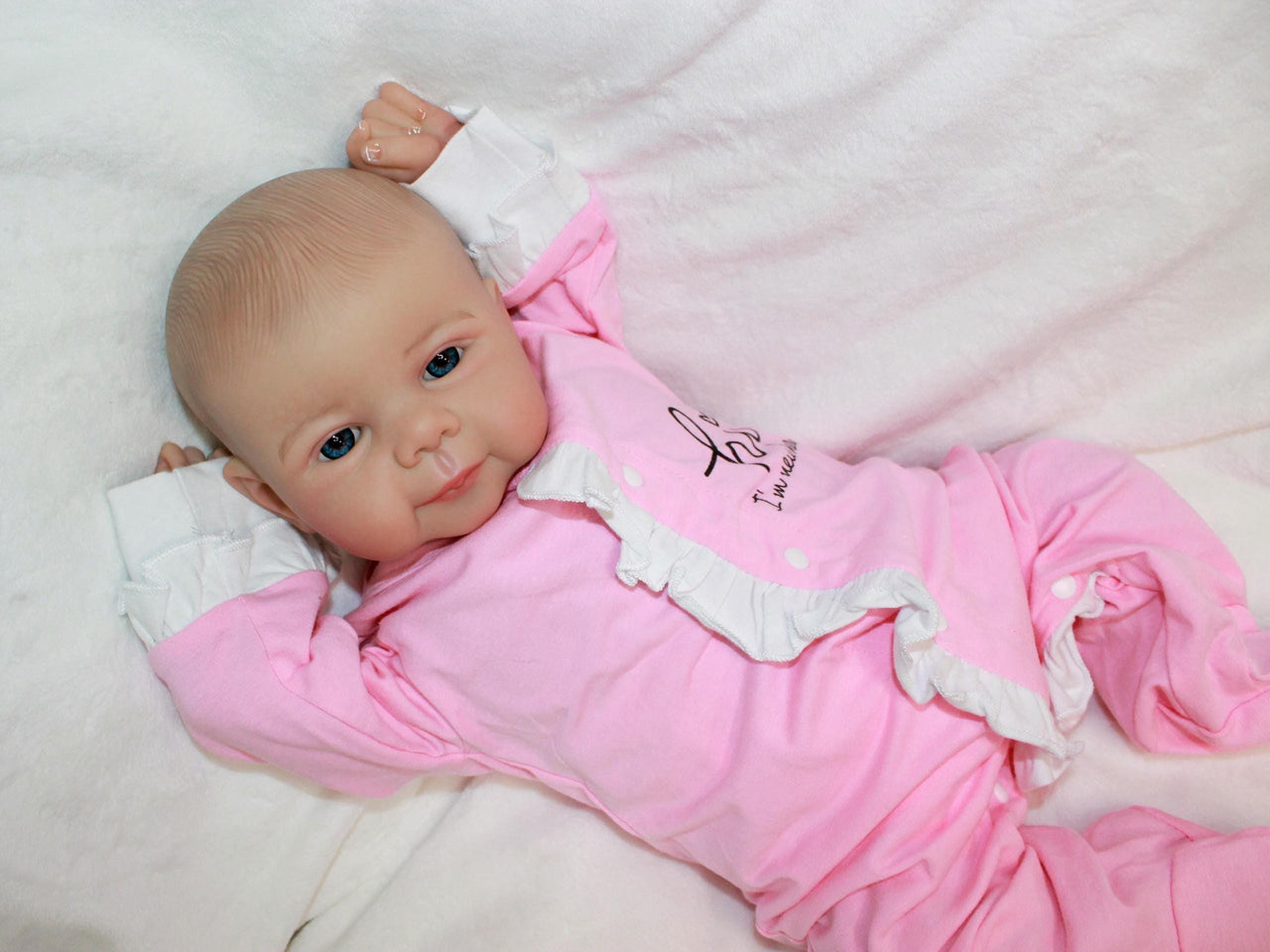 A baby doll lying on a pristine white sheet, emphasizing its adorable appearance and gentle colors.
