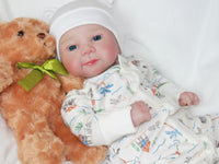 Thumbnail for A baby doll positioned on a clean white sheet, highlighting its charming design and soft textures.