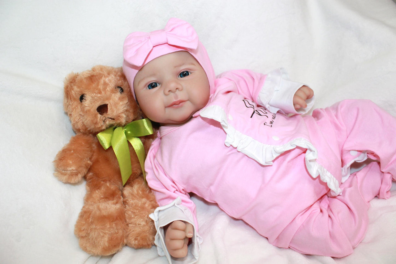 A baby doll positioned on a clean white sheet, highlighting its charming design and soft textures.