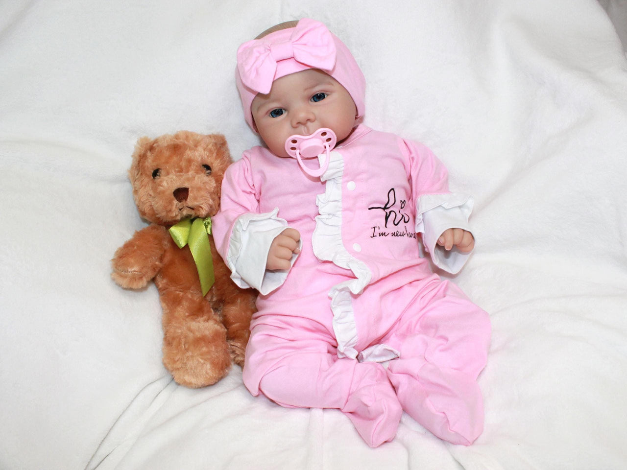 A baby doll lying on a pristine white sheet, emphasizing its adorable appearance and gentle colors.