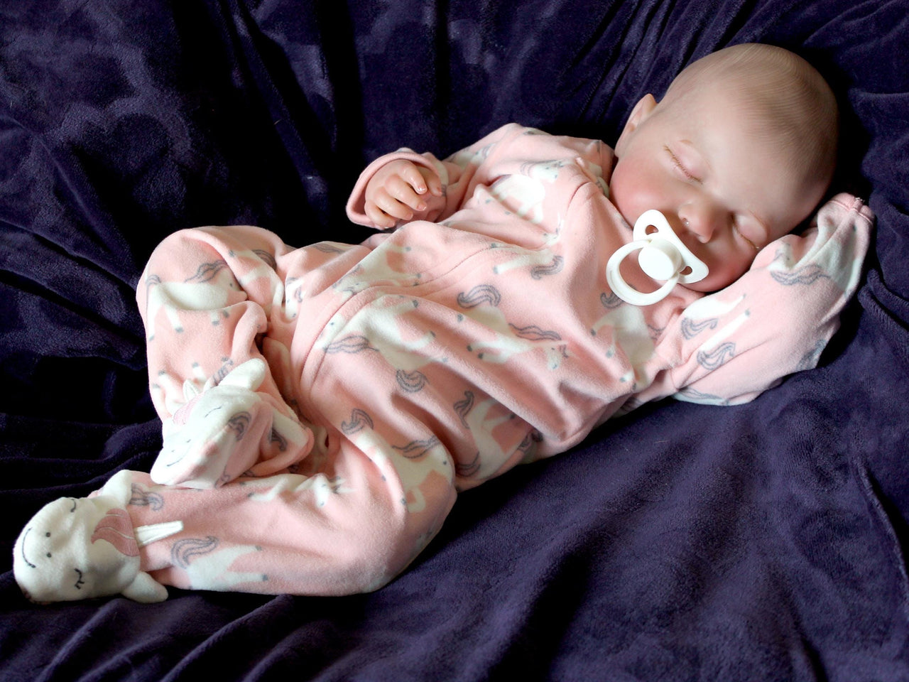 A baby doll resting on a soft purple couch, showcasing its delicate features and bright clothing.