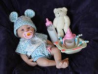 Thumbnail for Lifelike reborn baby doll with blue eyes wearing blue bear-print outfit and matching bunny ear hat, realistic handmade newborn doll