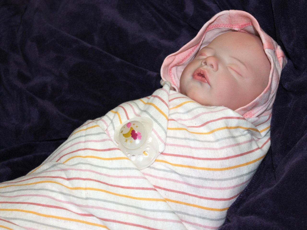 A sleeping baby doll rests on a fluffy white blanket, evoking a sense of calm and innocence.