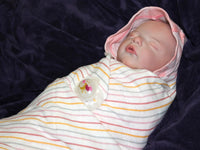 Thumbnail for A sleeping baby doll rests on a fluffy white blanket, evoking a sense of calm and innocence.