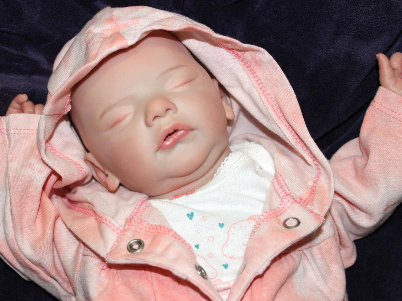 A sleeping baby doll rests on a fluffy white blanket, evoking a sense of calm and innocence.