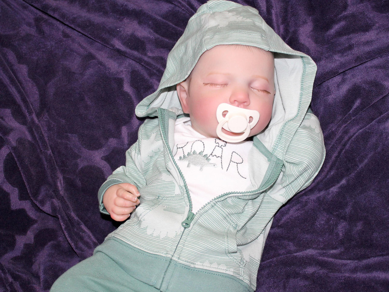 A baby resting on a bed, adorned with a charming hat, surrounded by cozy blankets.