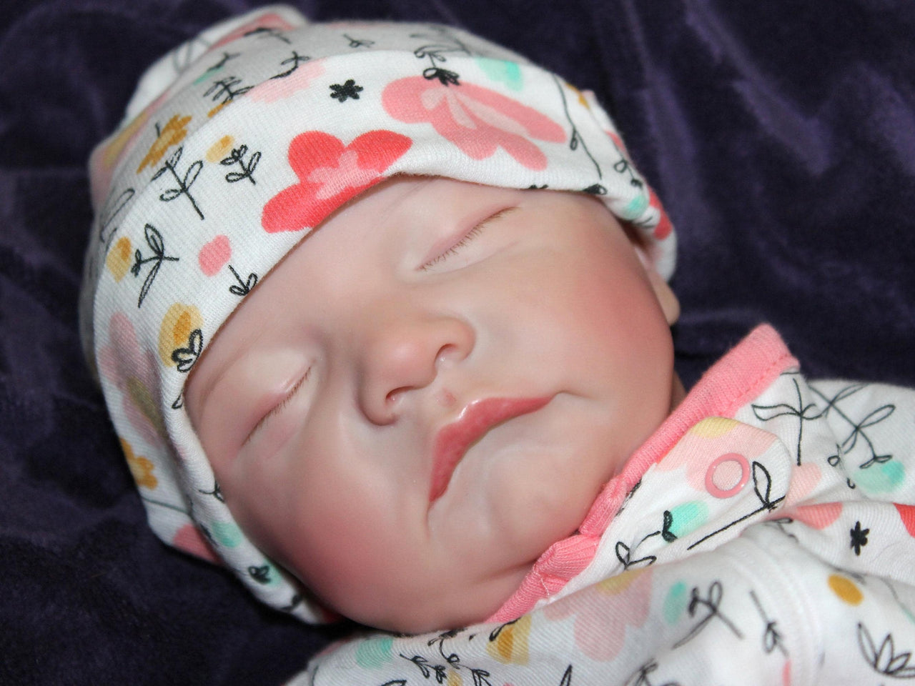A baby in cozy pink blanket, resting on their back with a calm demeanor.