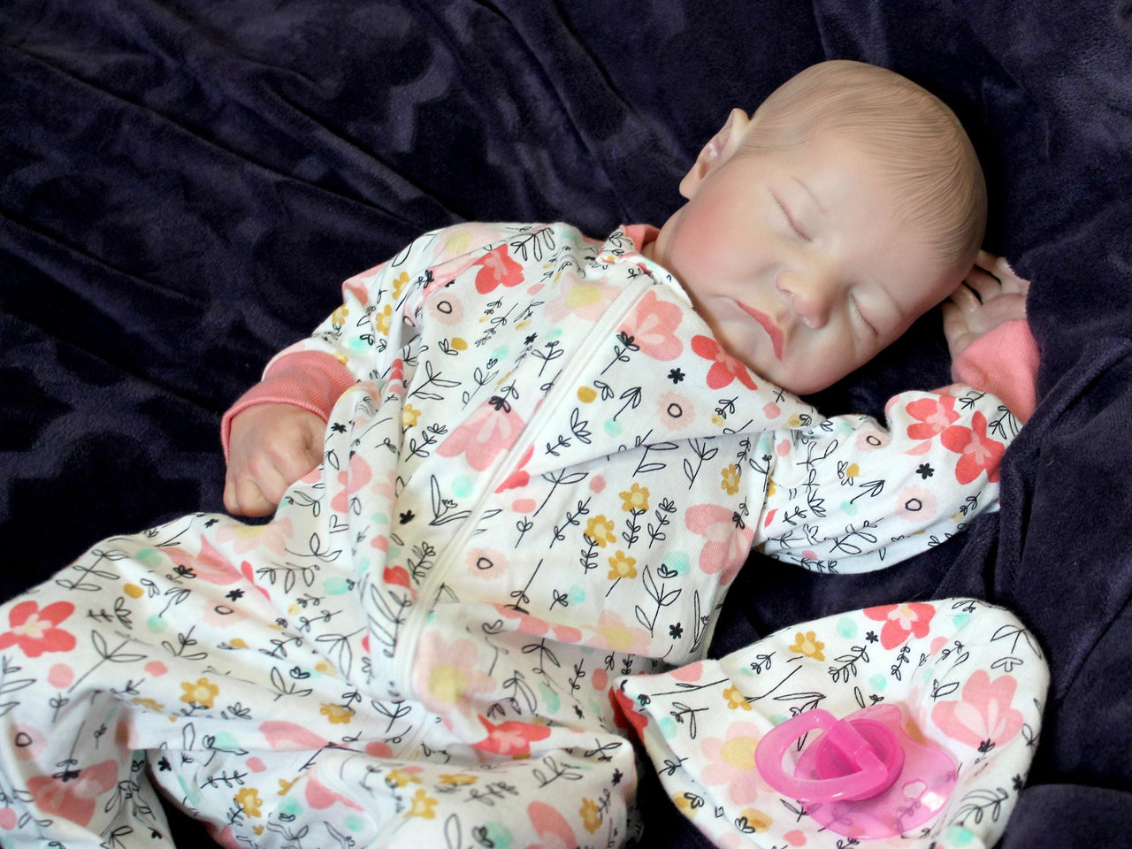 A baby dressed in flowered pajamas, comfortably lying down with a serene expression.