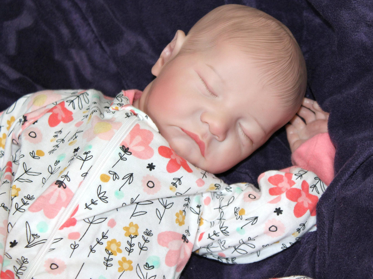 A baby dressed in flowered pajamas, comfortably lying down with a serene expression.