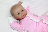 Thumbnail for A baby doll positioned on a clean white sheet, highlighting its charming design and soft textures.