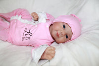 Thumbnail for A baby doll positioned on a clean white sheet, highlighting its charming design and soft textures.