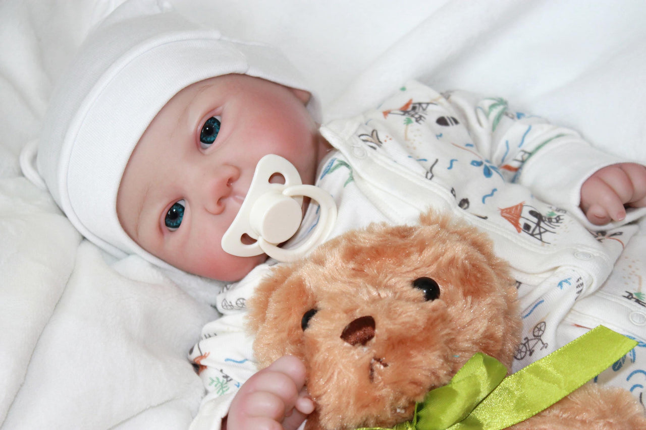 A baby doll lies on a bed next to a teddy bear, evoking a sense of childhood comfort and companionship.