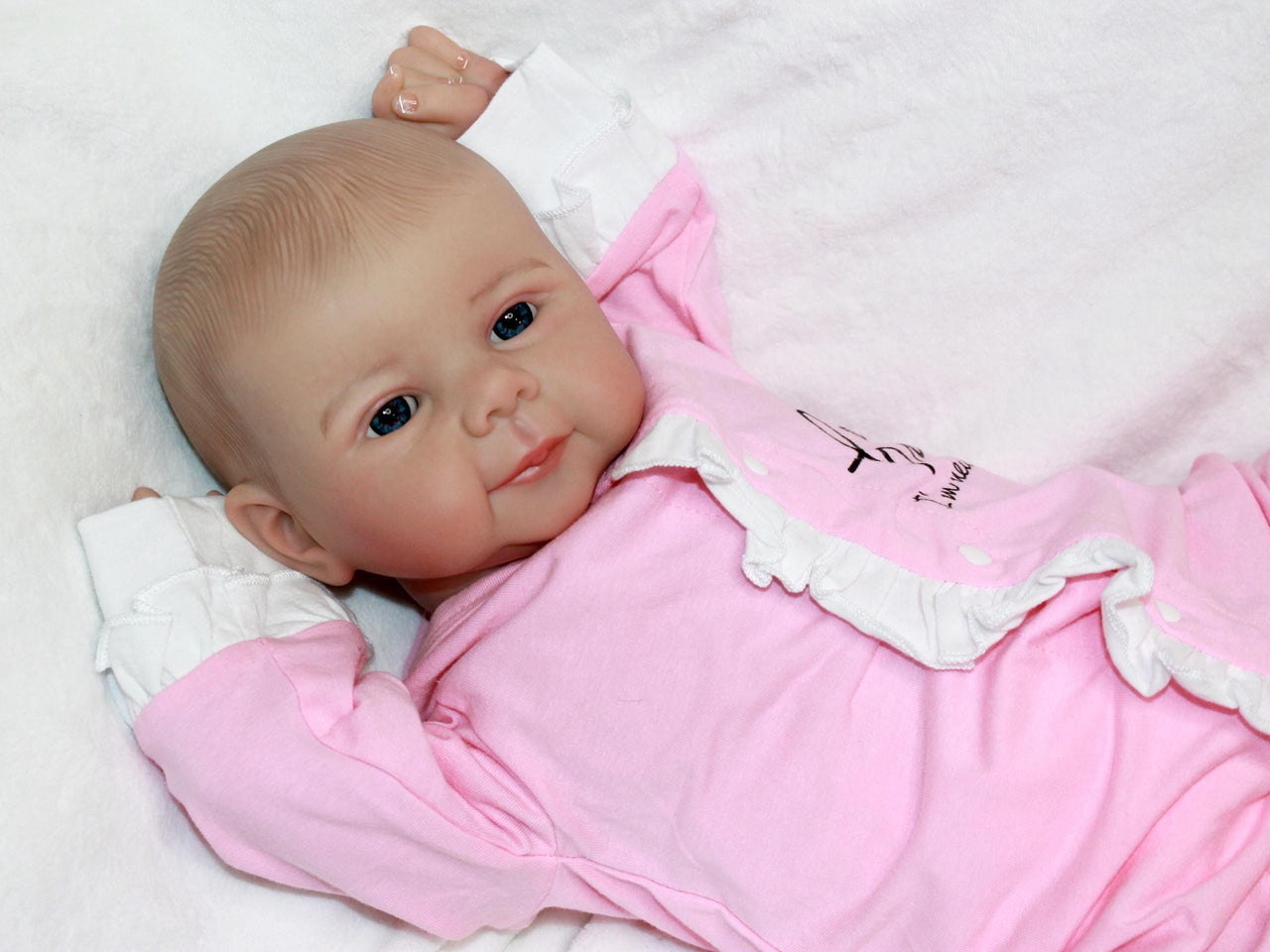 A baby doll lying on a pristine white sheet, emphasizing its adorable appearance and gentle colors.