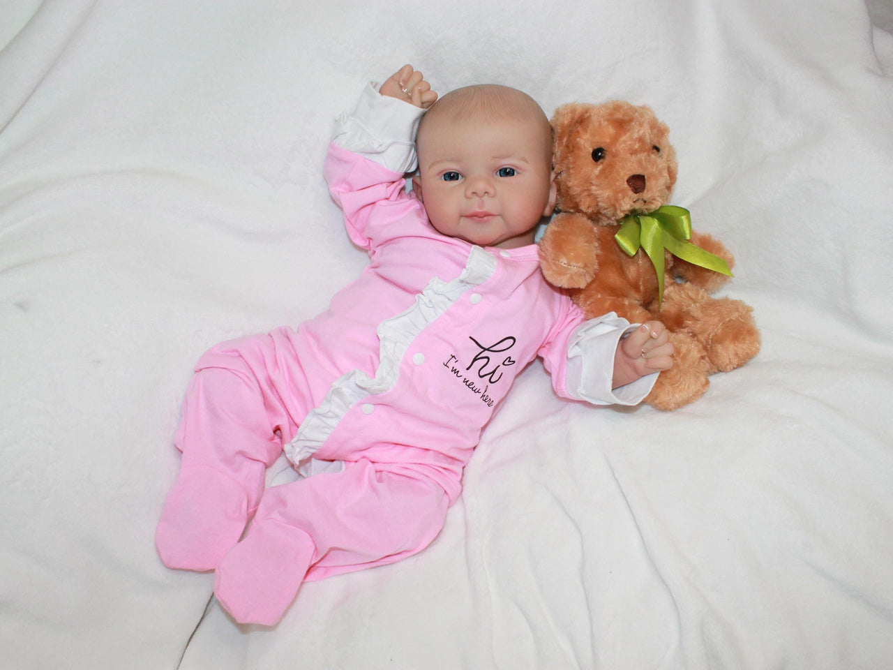 A baby doll lying on a pristine white sheet, emphasizing its adorable appearance and gentle colors.