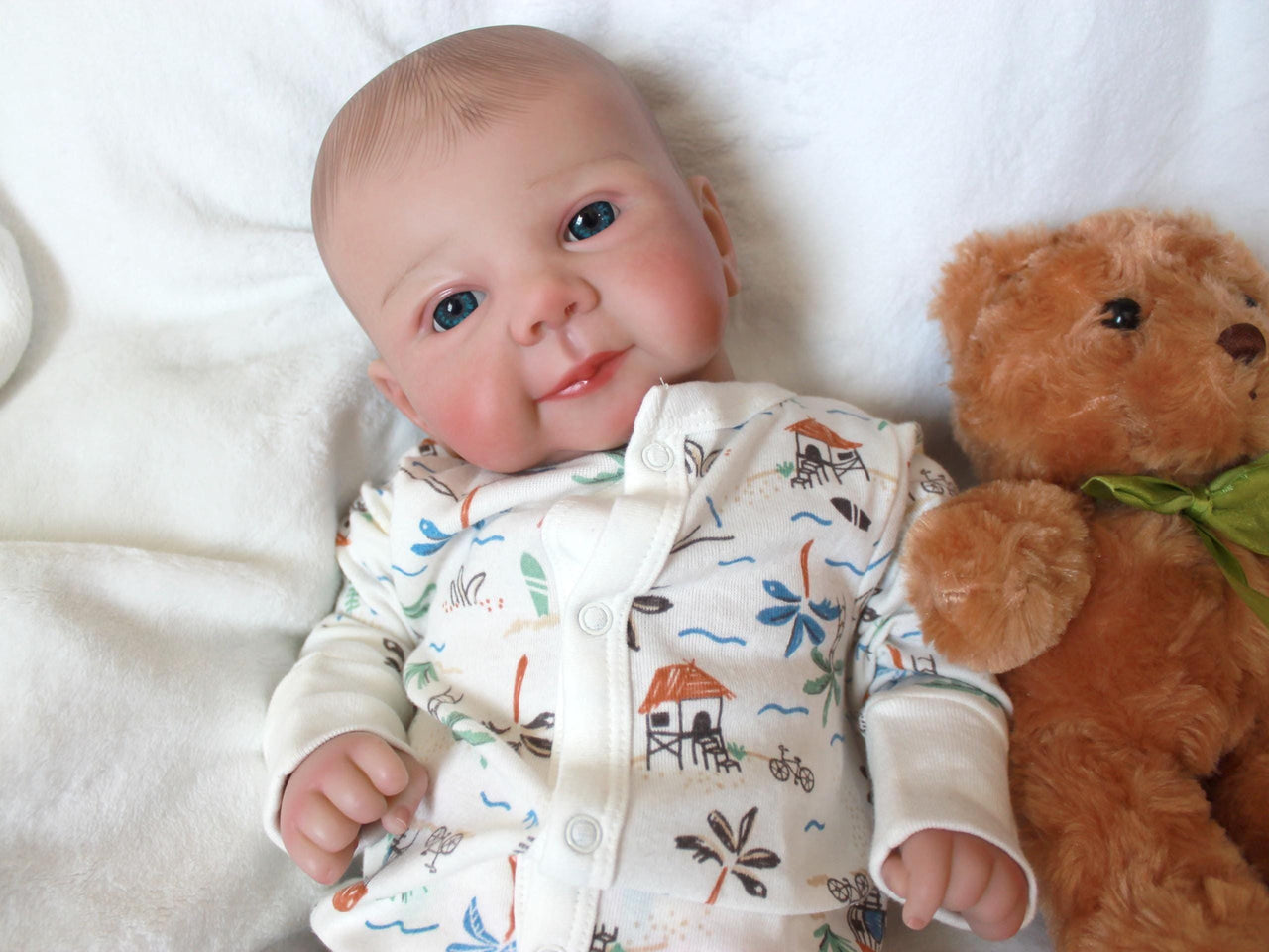 A baby doll resting on a soft white sheet, showcasing its delicate features and clothing.