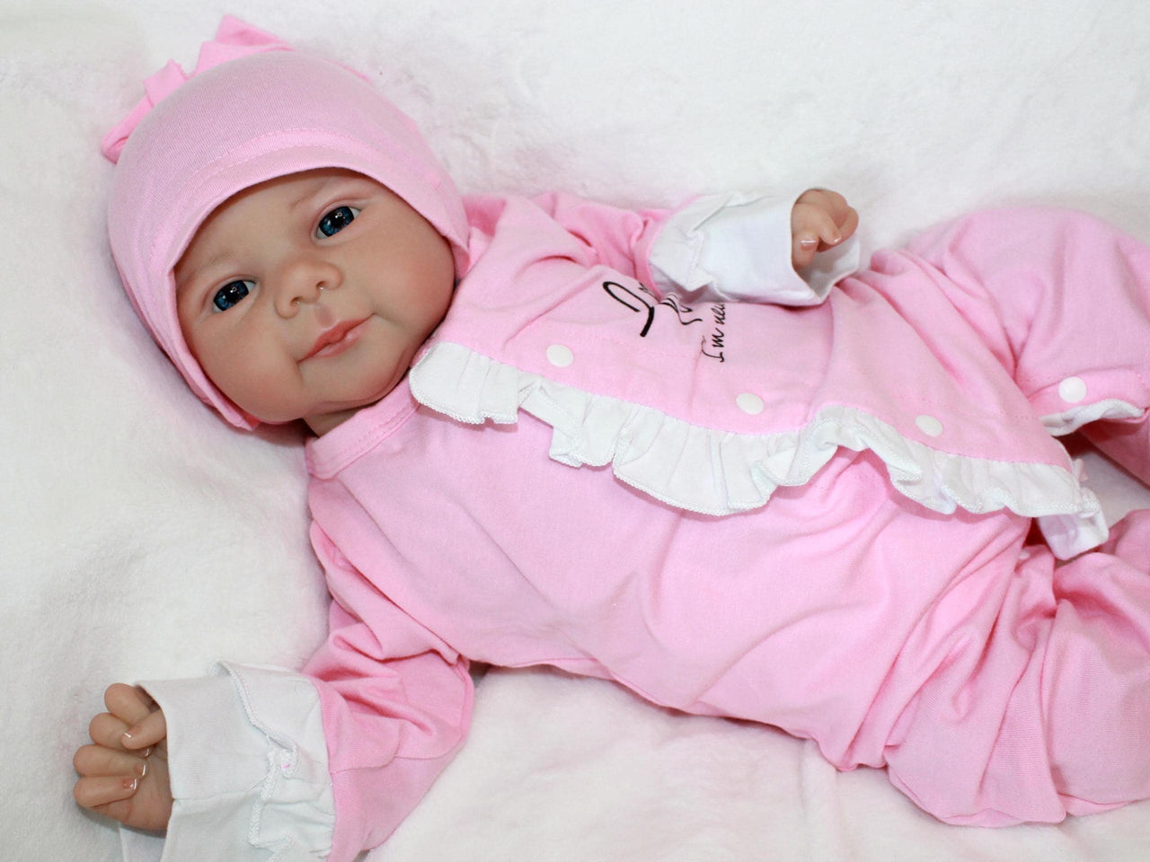 A baby doll lying on a pristine white sheet, emphasizing its adorable appearance and gentle colors.