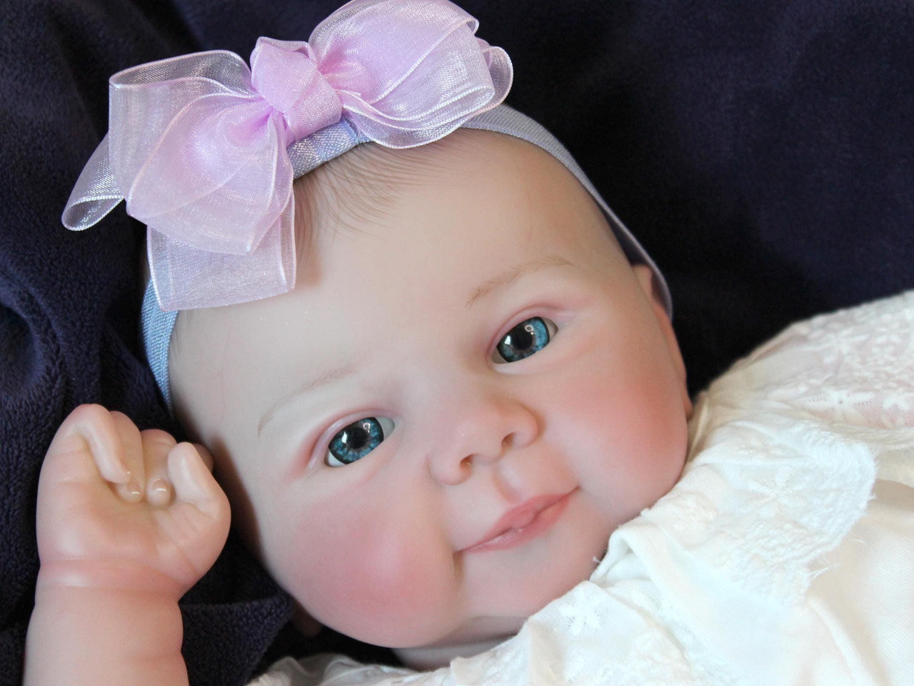A baby doll positioned on a clean purple sheet, highlighting its charming design and soft textures.