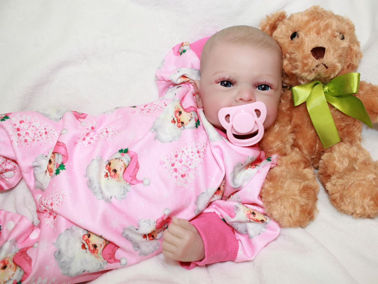 A baby doll with a pacifier rests on a soft bed, showcasing its delicate features and cozy surroundings.