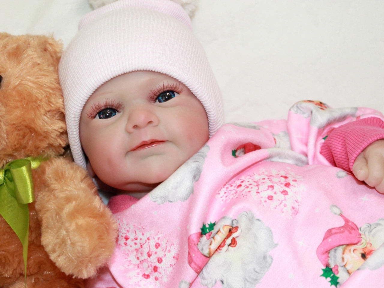 A baby dressed in pink cuddles a teddy bear, exuding joy and innocence.