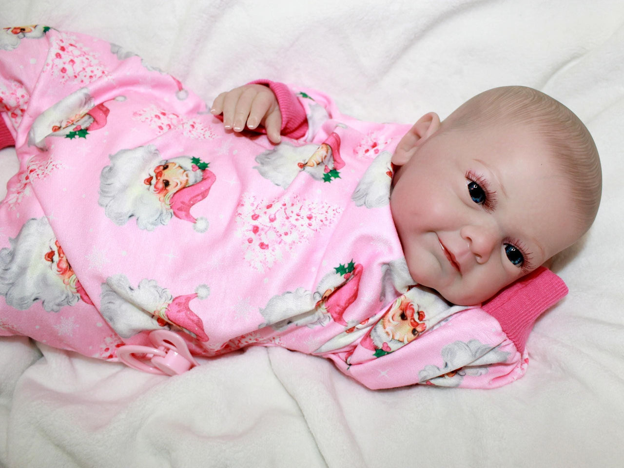 A baby doll wearing pink pajamas is positioned on a bed, highlighting a serene and nurturing environment.
