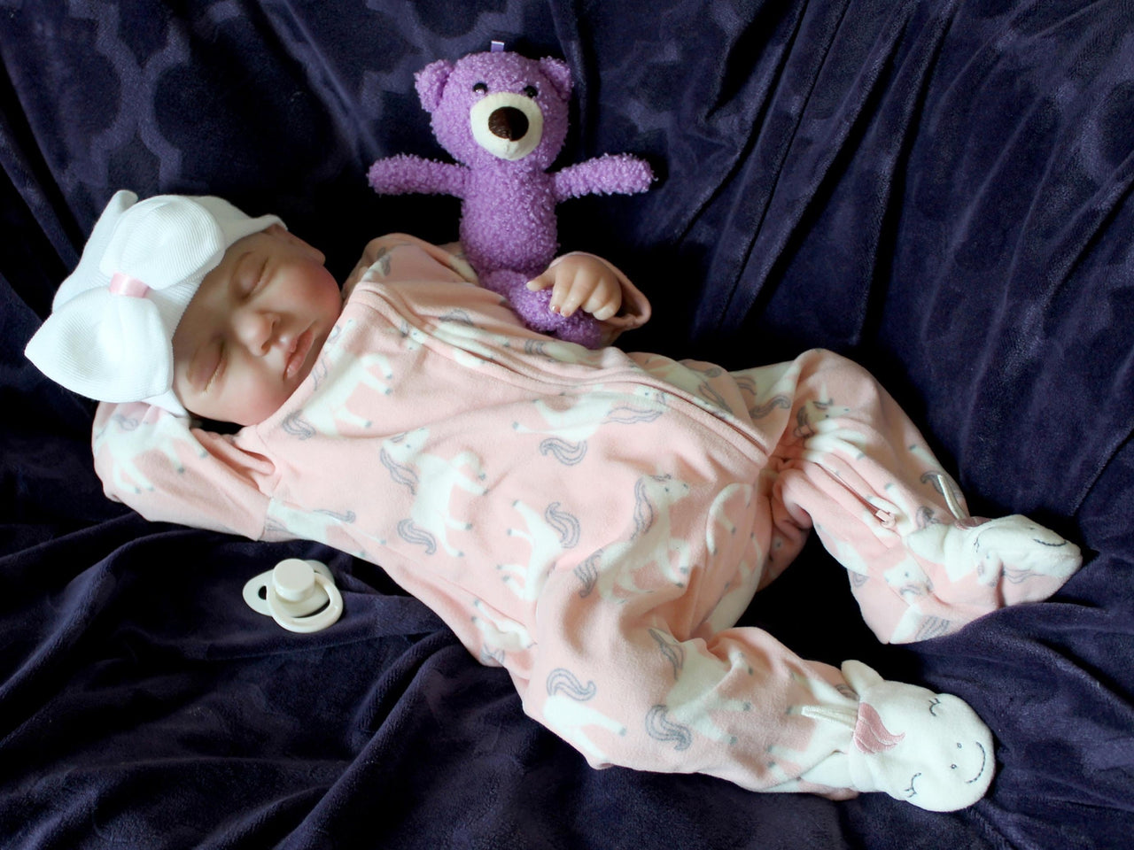 A baby doll resting on a soft purple couch, showcasing its delicate features and bright clothing.