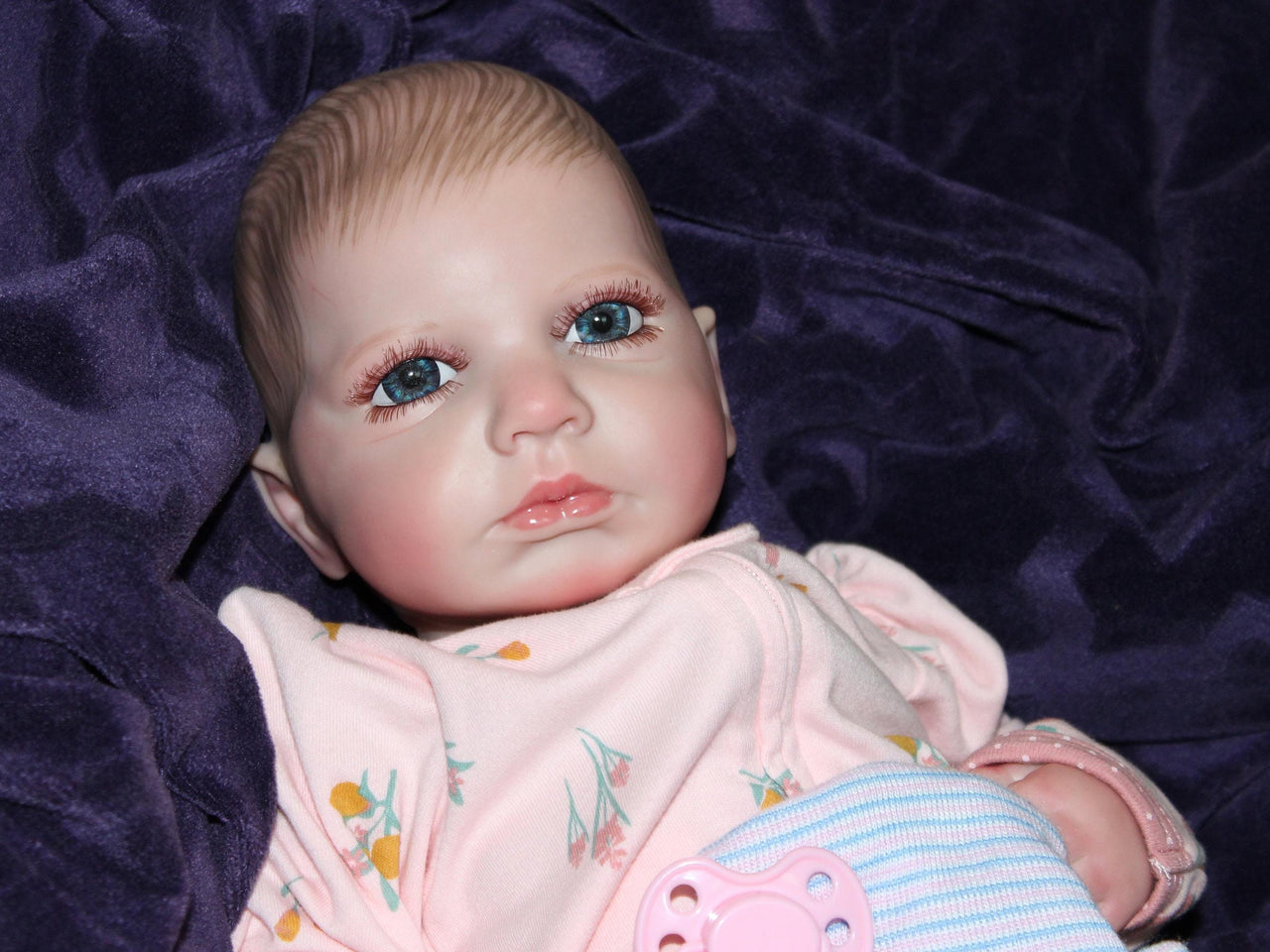 Weighted reborn baby doll with blue eyes and soft cloth body, therapy doll designed for comfort, realism, and relaxation