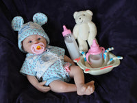 Thumbnail for Lifelike reborn baby doll with blue eyes wearing blue bear-print outfit and matching bunny ear hat, realistic handmade newborn doll