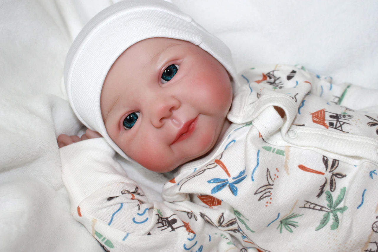 A baby doll positioned on a clean white sheet, highlighting its charming design and soft textures.