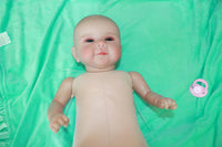 Thumbnail for A baby doll positioned on a clean green sheet, highlighting its charming design and soft textures.