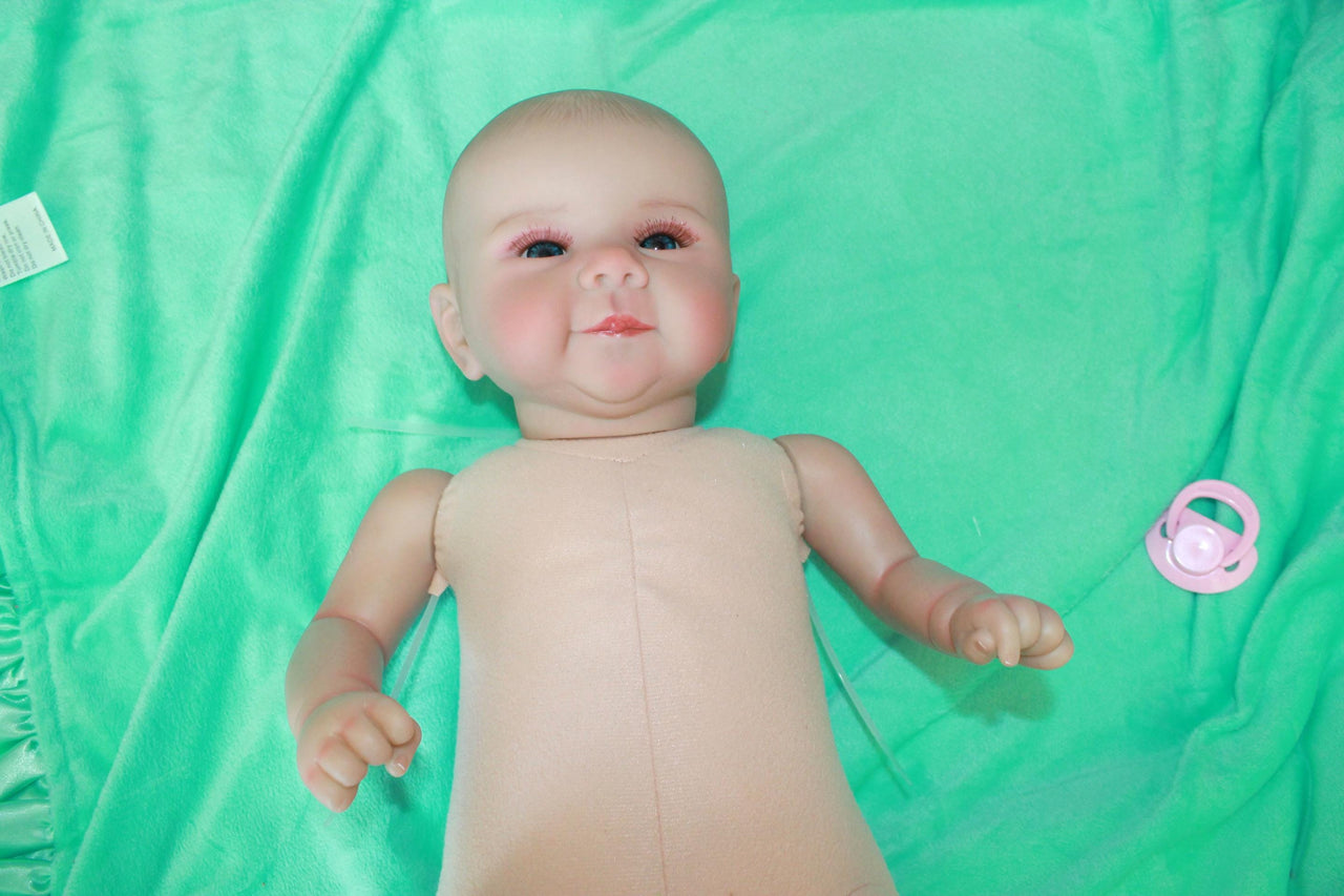 A baby doll lying on a pristine green sheet, emphasizing its adorable appearance and gentle colors.