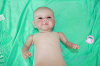 Thumbnail for A baby doll lying on a pristine green sheet, emphasizing its adorable appearance and gentle colors.
